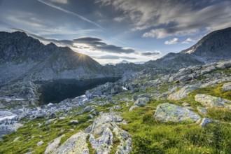 Sunrise over a mountain landscape with wo, ken rocky terrain and mountain lake, Krimml, Salzburg,