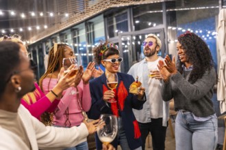 Multi-ethnic friends clasping and singing birthday song to a woman standing outside a night bar
