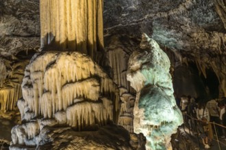 Tourists marveling at illuminated stalactites and stalagmites formations inside the famous postojna