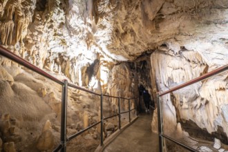 Tourists walking on a footpath and exploring the magnificent postojna cave in slovenia, a popular