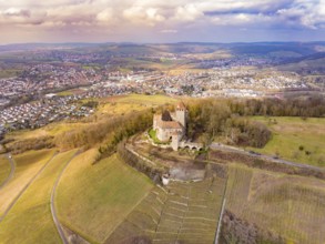 An impressive view of the castle and the surrounding fields, surrounded by a village and hills,
