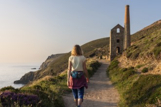 A hiker on the trail to the ruins of Wheal Coates, a former tin mine. The Towanroath Shaft. Pink