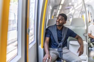 Casual and young african businessman sitting on the metro looking through the windows