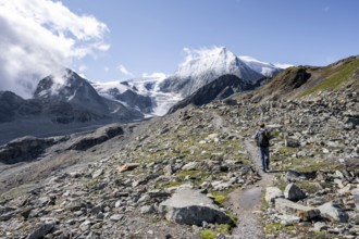 Mountaineer on a hiking trail, behind glacier Glacier de Cheilon and summit Mont Blanc de Cheilon,