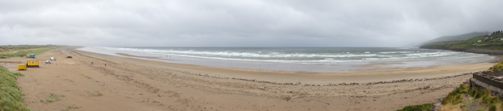 Wide sandy beach with waves under a cloudy sky, coastal panorama, quiet atmosphere, Inch Beach