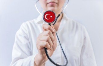 Female doctor holding stethoscope with Turkey flag. National Health System of Turkey