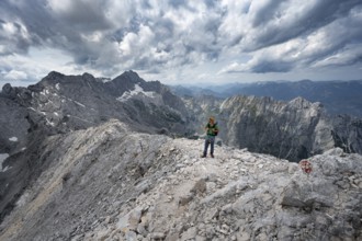 Mountaineer with helmet on a narrow rocky path, crossing the Jubiläumsgrat, view of Zugspitze and