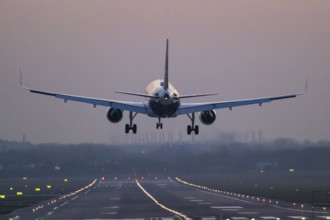 An aeroplane lands on an illuminated runway at dusk, Helmut Schmidt Airport, Fuhlsbüttel Airport,