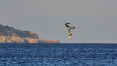 Wingfoiller, surfer in the air over the sea near a coast with cliffs, windsurfer, Meltemi