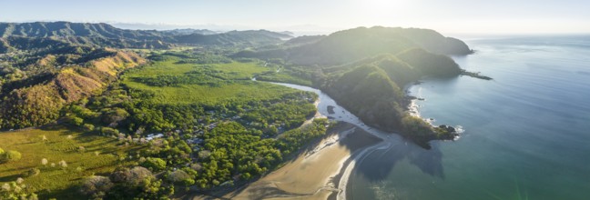 Aerial view, panorama of a coastal region with mountains, beach and forest in natural light,