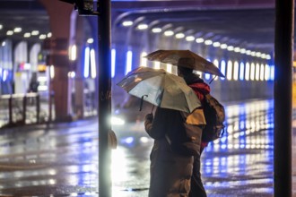 Illuminated subway at the main railway station, pedestrians at a pedestrian crossing, rainy