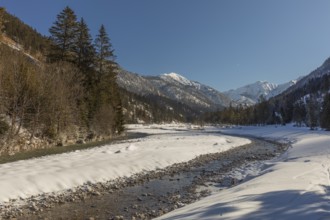 The Riss creek flowing through a snow covered landscape in the Eng valley. Sunny day with blue sky