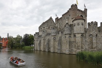 Tourists in a boat looking at Gravensteen Castle, Ghent, Flanders, Belgium, Europe