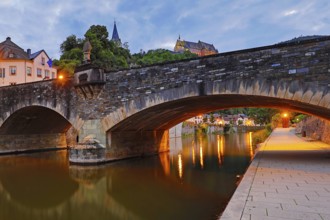 Town view of Vianden with the old stone bridge over the river Our and the castle in the evening,