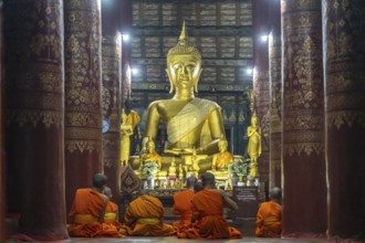 Monks praying in front of the great Buddha in the temple Wat Pak Khan Khammungkhun, Luang Prabang,