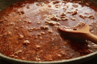 Cooking, bolognese sauce, in a frying pan, stirring with a wooden spoon, tomato meat sauce,