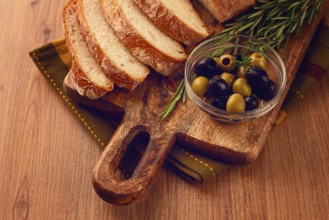 Sliced ciabatta, on a chopping board, with rosemary and olives, Italian bread, close-up, Italian