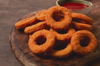 Crispy chicken rings, fried, on a wooden board, close-up