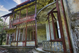 Sky replaced, Abandoned, dilapidated building with red doors and rusty railings, graffiti on the