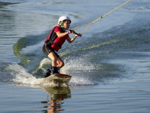 Boy or girl with wakeboard in the lake, red waistcoat, water sports, water skiing in the wake park