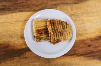 Top view of two meat and chicken panini on wooden table
