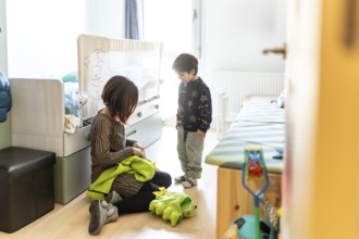 Mother and son playing together at home, preparing a dinosaur costume for a fun game in their