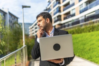Portrait of a caucasian elegant mature adult thoughtful businessman with laptop in the city