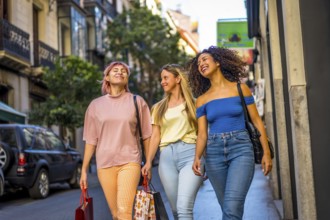 Happy female friends walking shopping along a modern city