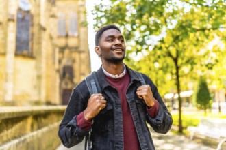 Happy young african man with casual clothes and rucksack enjoying walking in the city