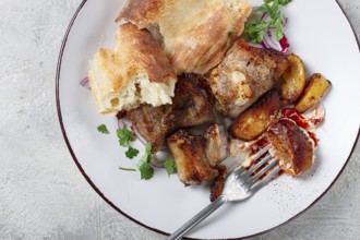 A plate with leftover pork kebab, with bread, on a white plate, close-up, there are no people