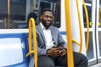 Young professional enjoying his commute, using a smartphone while traveling through the metro,
