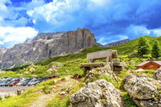 Weathered wooden bench inviting rest while offering breathtaking views of sella pass in the italian