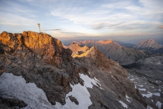 Summit of the Zugspitze with golden summit cross, alpenglow at sunset, Northern Limestone Alps,