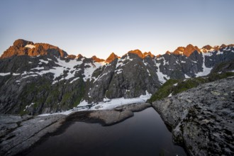 Rocky mountain peaks and Trollfjordvatnet with snow, small pond in moorland at Trollfjord Hytta,