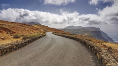 Serpentine road in a barren mountain landscape with clouds in the sky near the Mirador del Rio,
