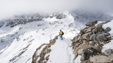 Mountaineers climbing the ridge of Piz Laviner, view of wintry mountain landscape, Grisons Haute