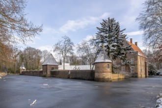 Moated castle Haus Welbergen surrounded by frozen water and snow-covered trees, Ochtrup-Welbergen,