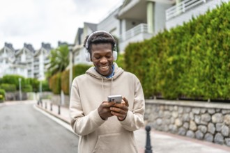 African young man using phone and listening to music in the city