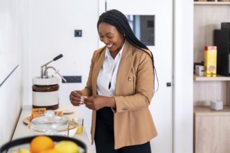 Smiling businesswoman preparing breakfast in hotel room during business trip, enjoying amenities