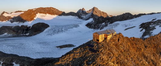 Atmospheric sunrise in a picturesque mountain landscape, alpenglow, aerial view, mountain hut