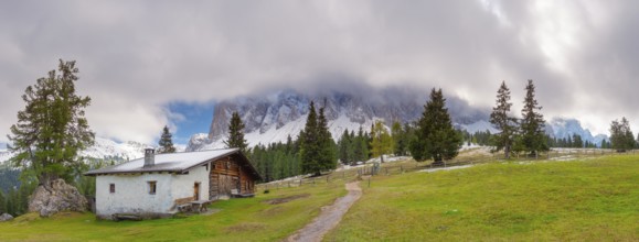 Panoramic view of the partly cloudy Geißler group with a hiking trail and a hut of the Glatsch Alm