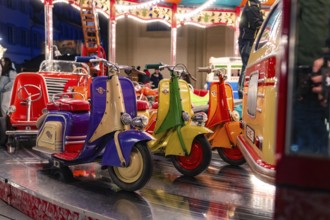 Colourful toy scooters on a fairground carousel at night, Christmas market Ludwigsburg, Germany,