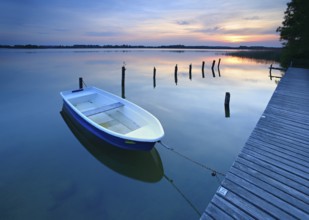 Sunset at Lake Schaalsee, jetty with rowing boat and wooden post in the water, Schaalsee Biosphere