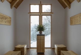 Interior of the chapel on the Glockenwanderweg trail with simple altar and small wooden benches,