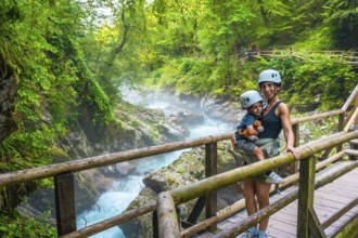 Mother carrying her child while visiting the stunning vintgar gorge near bled, slovenia, enjoying a