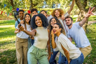 Multi-ethnic friends taking selfie with portable camera and tripod embraced together in a park