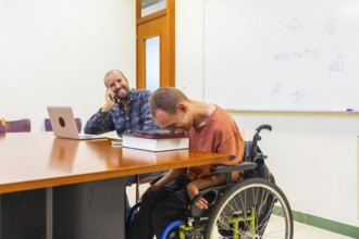 Happy teamwork with a man with disability using tablet in a coworking meeting