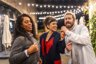 Man singing karaoke with multi-ethnic friends at terrace of bar during night party