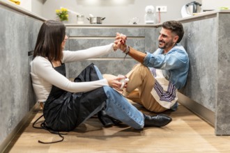 Chefs enjoying a coffee break, holding hands and smiling at each other, sitting on the kitchen