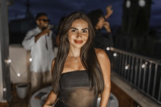 Beauty seductive woman in night dress dancing during night roof party with multiracial friends